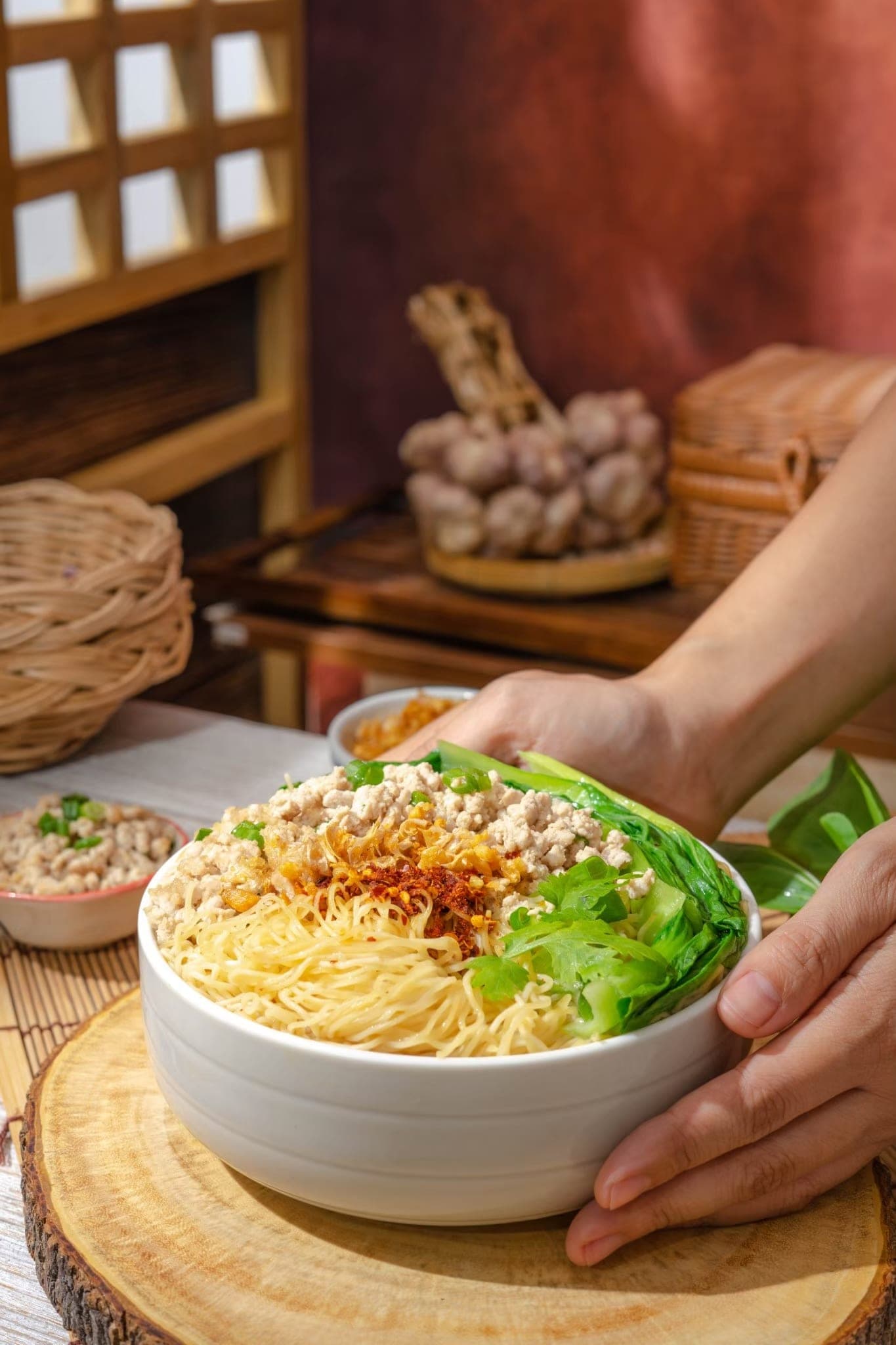 A bowl of cooked Cintueng noodles topped with ground pork, fried garlic and greens